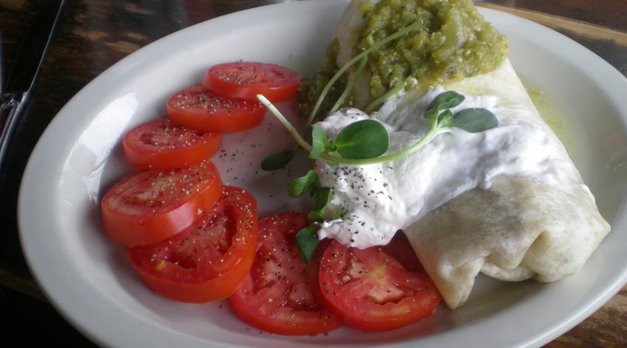 Breakfast burrito with salsa verde and slice tomato
