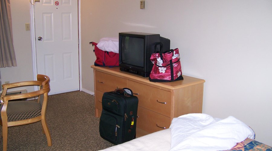 TV, bare walls, minimal furniture, no suitcase stand.