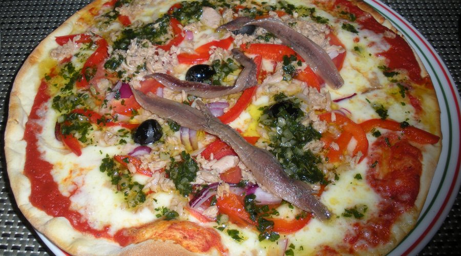 Nicoise pizza with mozzarella, tuna, anchoives, olives, bell peppers, garlic, and onions