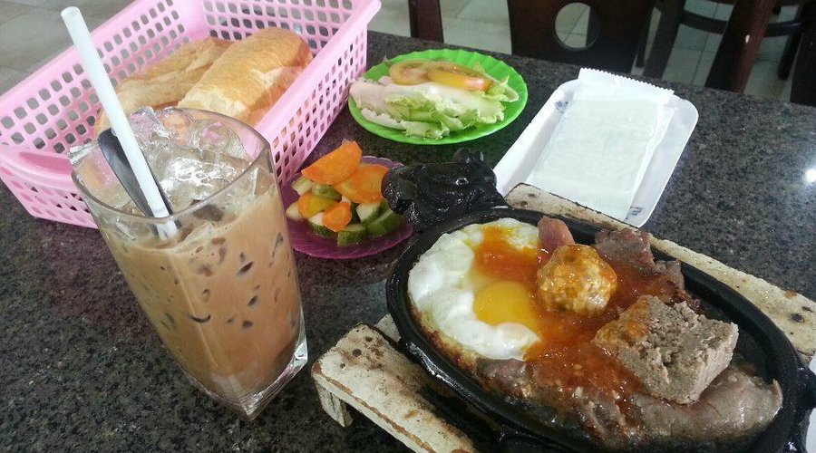 The "Dac Biet" steak with fried egg, meatball, and pate, accompanied by vegs & bread. + Cafe sua