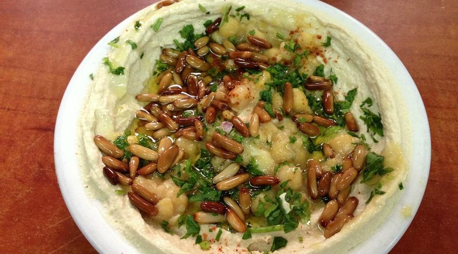 A bowl of humus with pine nuts