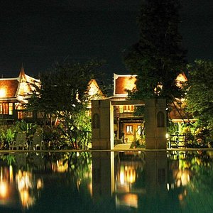 swimming pool with thai house in the background by night