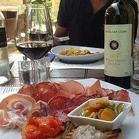 Tagliere di affettati toscani e pappardelle alla chianina. Il bicchiere di Sassicaia viene servi
