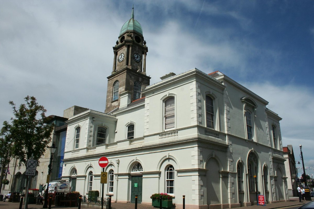 The Irish Linen Centre & Lisburn Museum building in Lisburn, a traditional stone building with arched windows, set against a blue sky with some clouds.