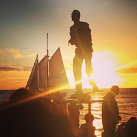 Performer and sail boat at sunset.