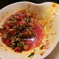 a half eaten dipping sauce bowl, chilli, corriander, nuts, chilli sauce, garlic, seasme seed +