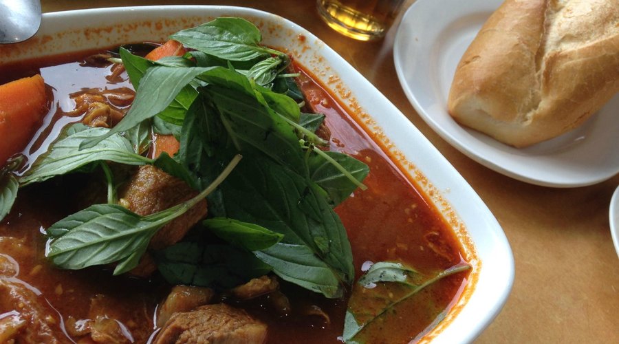 spicy goat stew curry with french bread roll