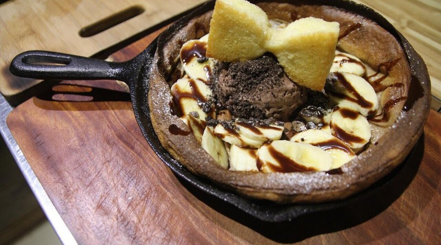 What a piece of artistic chocolate ice cream served with banana slices on a waffle resting on a 