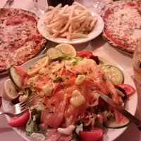 Smoked salmon salad and pizzas behind