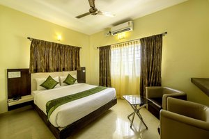 Daffodil Suites in Bengaluru, image may contain: Bed, Furniture, Chair, Ceiling Fan