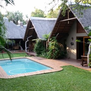 View across lawns and pool to the Leopard Cottage and lapa.