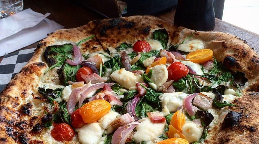 Spinach Pizza with walnut pesto, bacon, cherry tomatoes and red onion