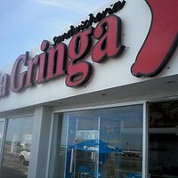 Entrada del local con opción de comer en la vereda con sombrillas
