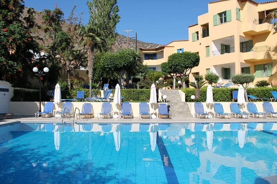 Outdoor swimming pool with lounge chairs and parasols in front of a hotel building.