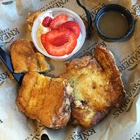Chunky cinnamon French toast with whipped cream, strawberries, and caramel maple syrup
