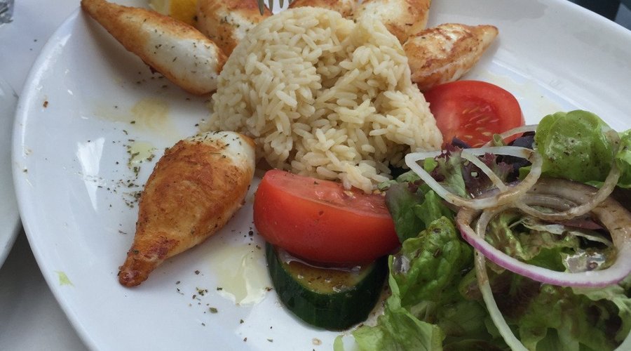 Piatto al riso, insalata e calamari. Sullo sfondo la pita all'aglio.