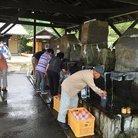 水汲み場は、看板のところのサイフォン式とこの屋根付きパイプ式とがある。いつもにぎわい、多くの容器を持ち訪れる