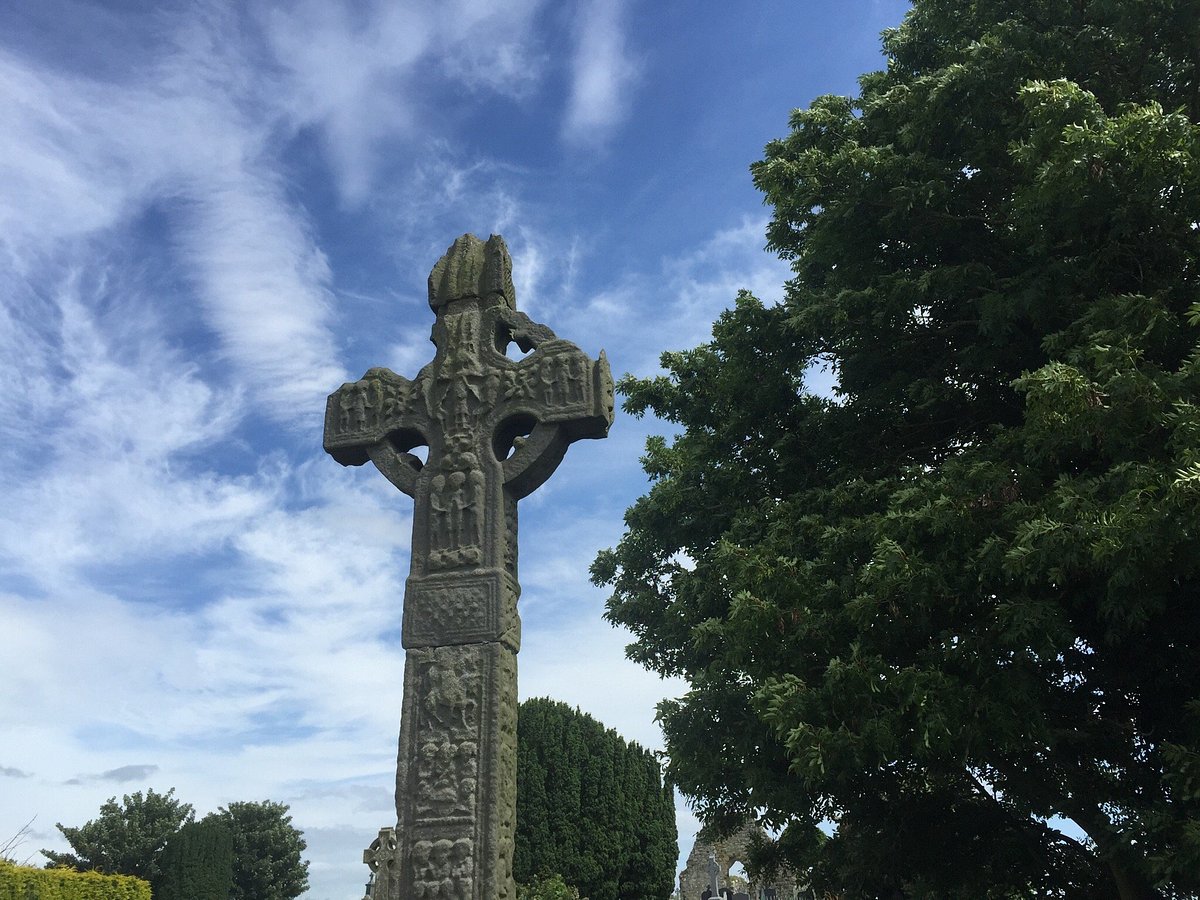 The tall, intricate Ardboe High Cross, standing against a forested background near Lough Neagh, close to Cookstown, Northern Ireland.