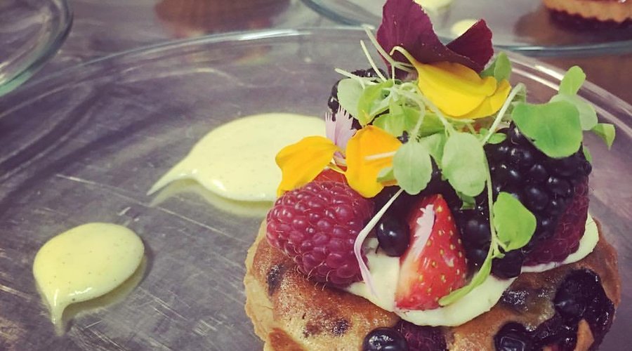 Färska bär, bakade i en tartelette med mandelcreme som toppas med råa bär, ätbara blommor från t