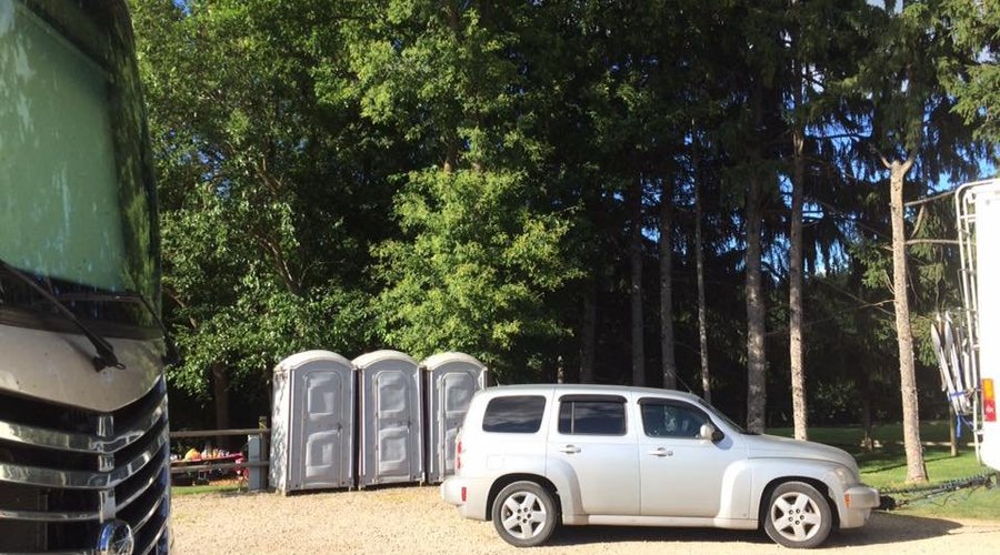 RV parked on gravel lot near porta potties