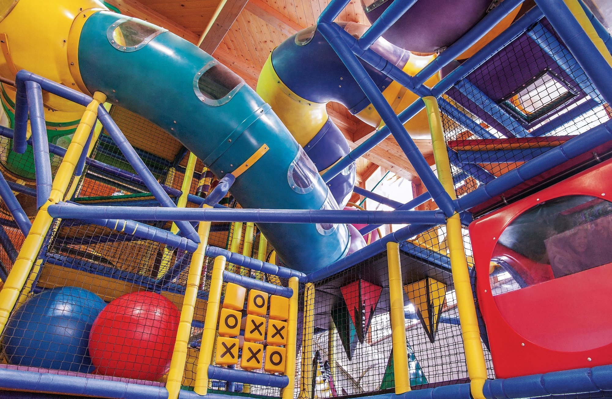 Weiterer Bereich des Indoor-Spielplatzes im Leading Family Hotel & Resort Alpenrose mit bunten Spielmodulen, Kletterwand und Tunneln