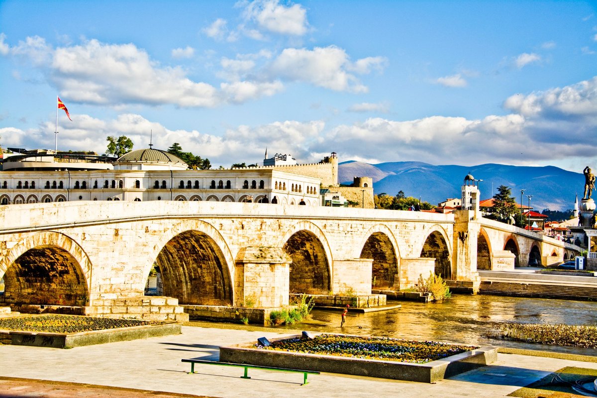 Skopje - Stone Bridge spanning the Vardar River with figures crossing and buildings in the background