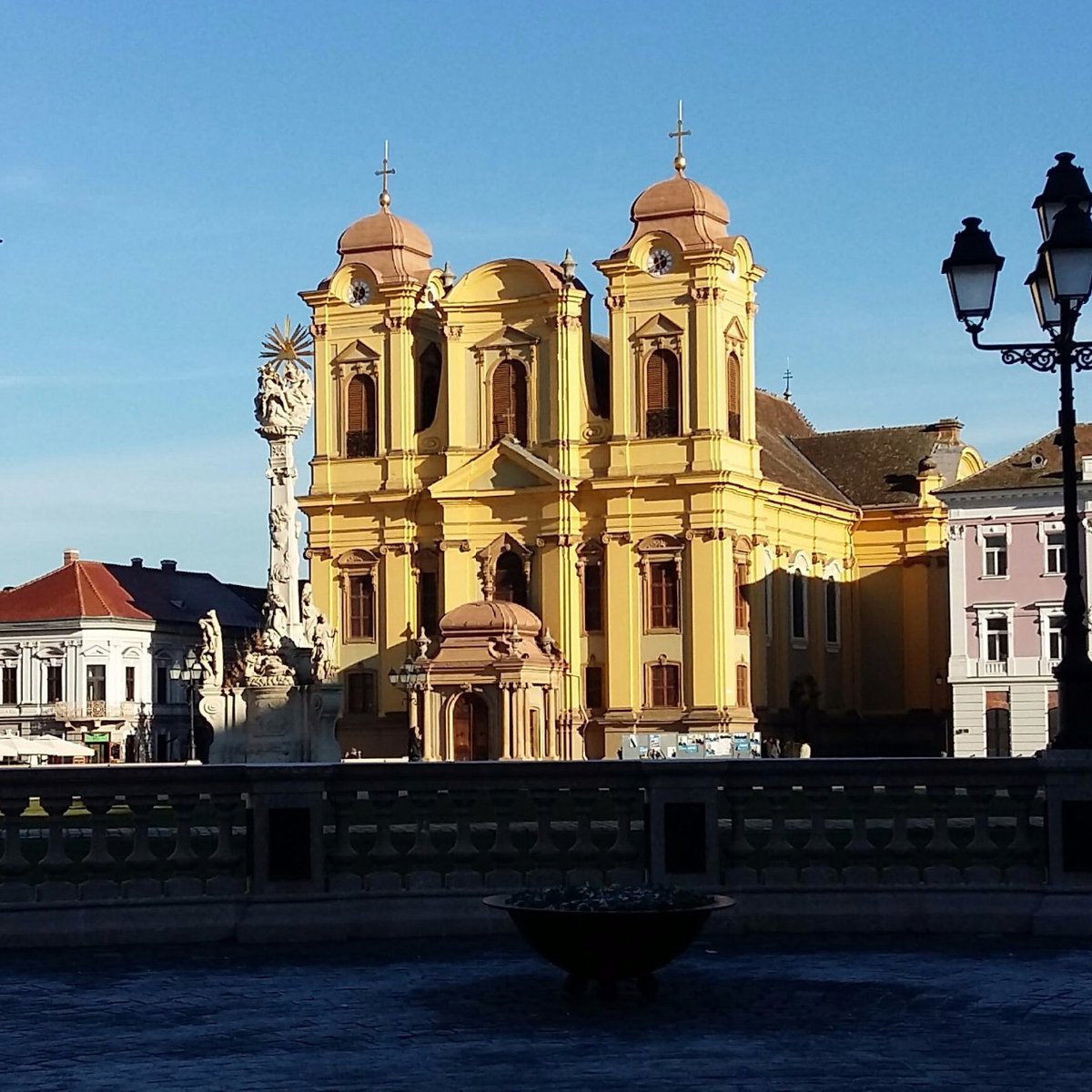 Unirii Square in Timisoara, featuring colorful baroque buildings and a central column.