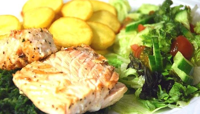 Łosoś po królewsku - Grillowany łosoś na szpinaku, mix sałat, złote talarki
