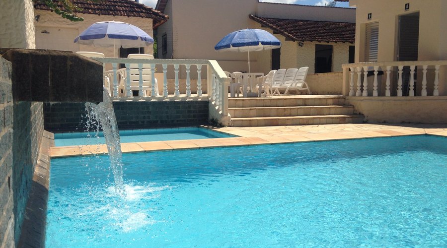 Área de lazer composta de uma piscina para adultos e outra infantil, com espreguiçadeiras.