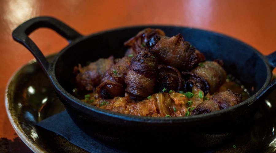 Bacon-wrapped Chorizo Stuffed Dates with Nappa Cabbage, Tomato Ragout and Guanciale.