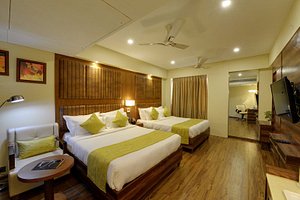 Super Inn Armoise Hotel in Ahmedabad, image may contain: Ceiling Fan, Electrical Device, Bed, Wood