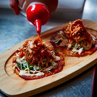 Costras - Soft, bite sized tacos with a cheese crust, topped with Pulled Pork, Black Beans and S