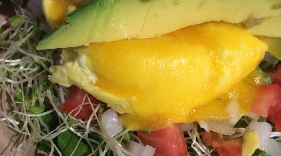 Steamed eggs and avocado atop a bed of fresh local sprouts, greens, tomatoes and onions.