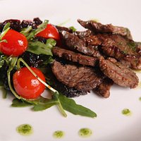 Филе говядины обжаренное на гриле подается с салатом из чернослива...