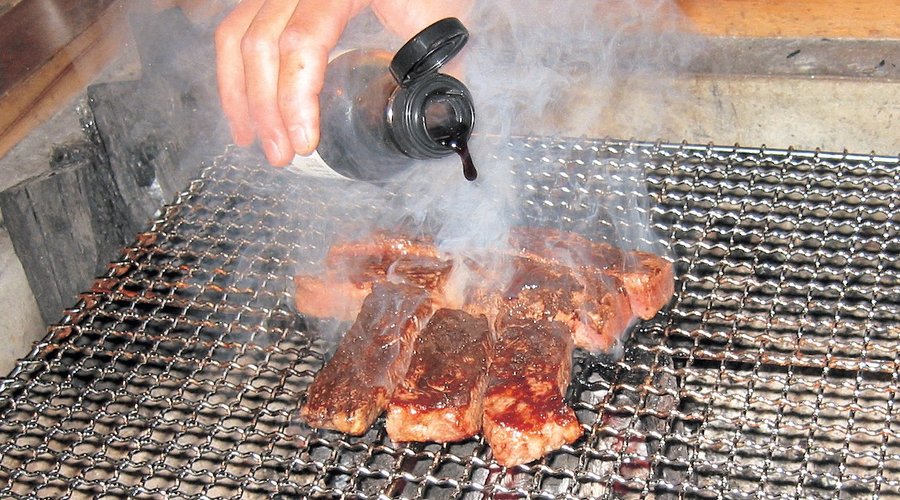 夕食時、いろり端で地元名産千屋牛（ちやぎゅう）の炭火焼。