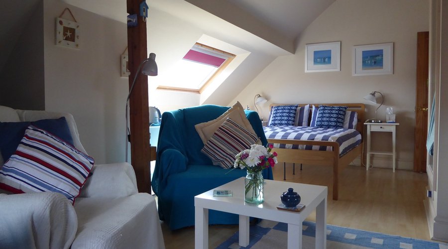 Seaside themed loftroom with king size and single bed & cosy seating area