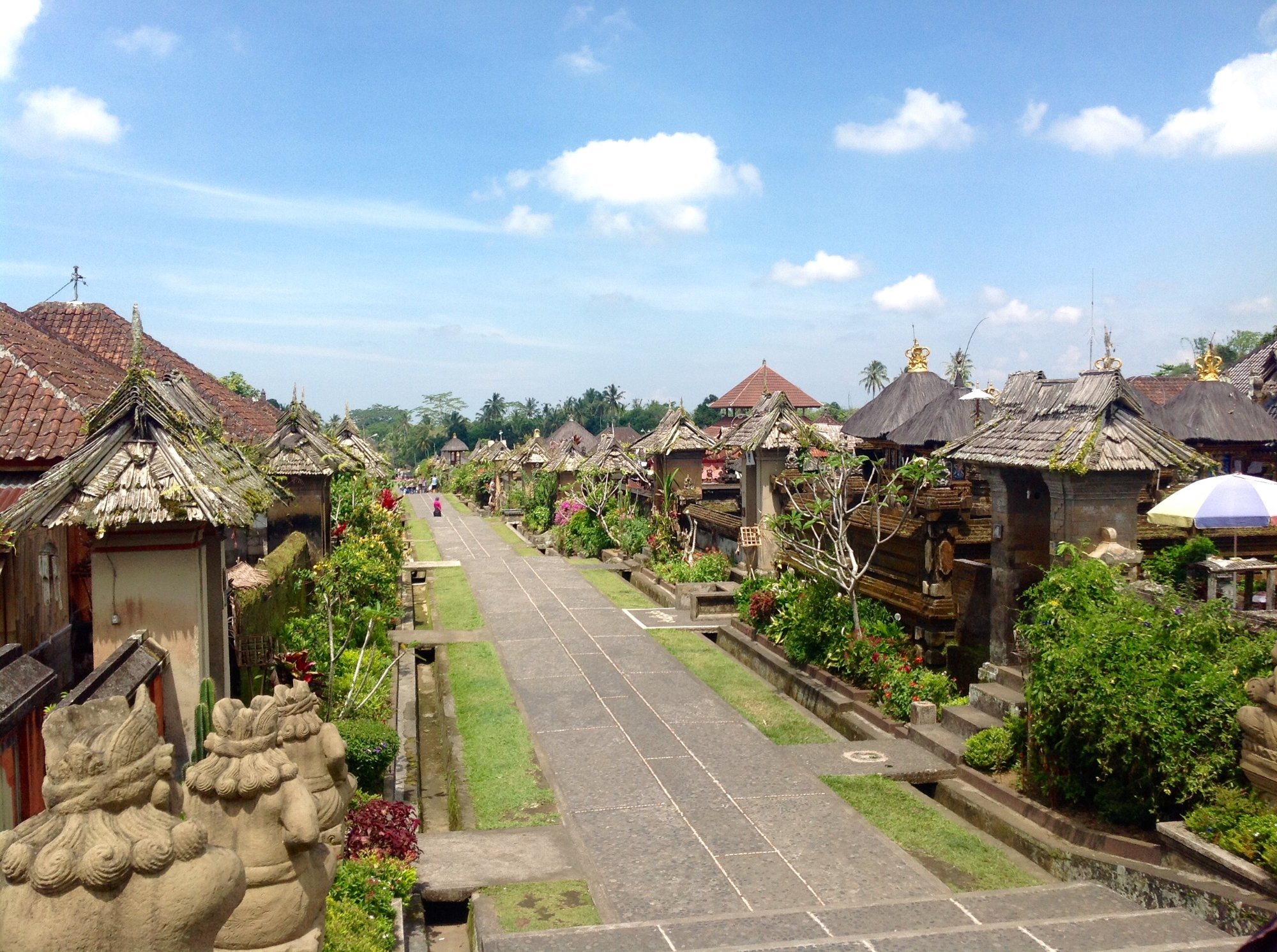 Stone-paved pedestrian street lined with identical traditional Balinese bamboo houses