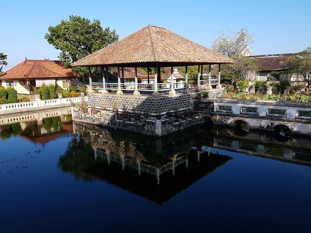 A traditional Balinese pavilion standing above a tranquil pond at Karangasem royal palace, a historical landmark often visited on a Bali heritage tour.