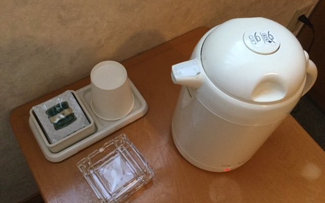 お茶セット：ティーパッグの緑茶と紙コップ、空のポットが置かれていました。