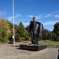 Marszałek Piłsudski patrzy na parkową zieleń.