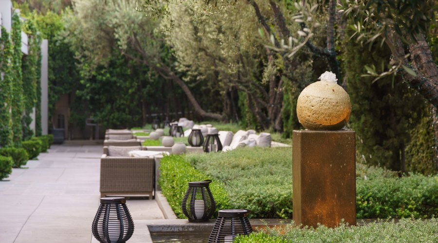 Water fountain in hotel terrace, tranquil outdoor seating area. 