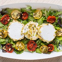 Ricotta in crosta di pistacchi e mandorle con pomodorini confit rossi e gialli su letto di insalata