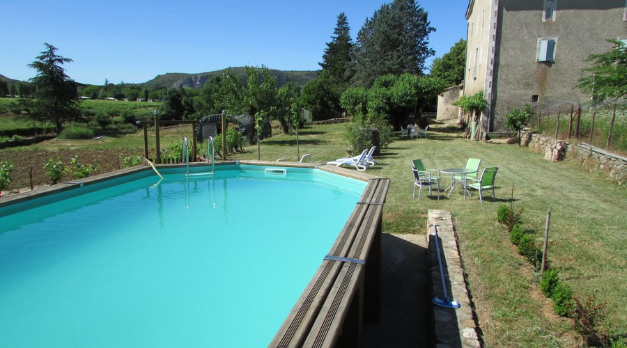 Piscine en bois de 4 m x 8 m. Le mas est tout à droite avec ses 3 niveaux typiques des anciennes fermes ardéchoises (cave et animaux en rez-de-chaussée, humains au premier et magnanerie au second (aménagée aujourd'hui en chambres d'hôtes).  