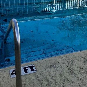 Nasty pool with cracks on pool deck.