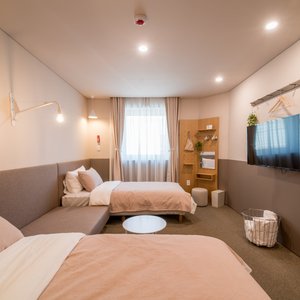 A unit for three containing a queen-size bed, a single bed and a bathroom. The interior of the unit is conceptualized by a toned-down gray and finished with wooden furniture that completes the relaxing atmosphere. The unit provides a comfortable stay for three as a family, members of a business trip or travel with friends.