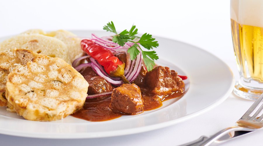 Traditional beef goulash with bread dumplings and a glass of Pilsner Urquell beer