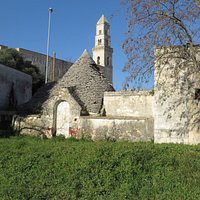 il bel campanile della chiesa dietro ad un trullo in primo piano