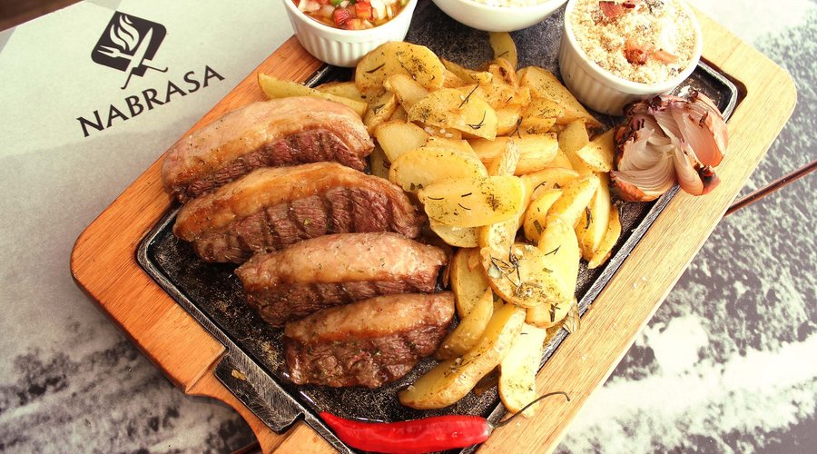 Picanha Completa. O prato tem o selo Bassi e vai parar na sua mesa muito bem acompanhado: Batata Rústica, Farofa de Alho na Manteiga com Bacon, Molho à Campanha e Arroz Branco.