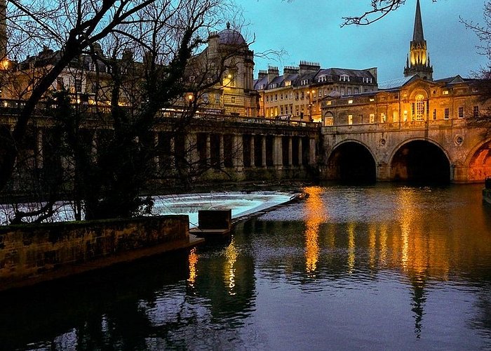 Las tranquilas aguas del río Avon circulando por Bath con la ciudad bellamente iluminada al atardecer.