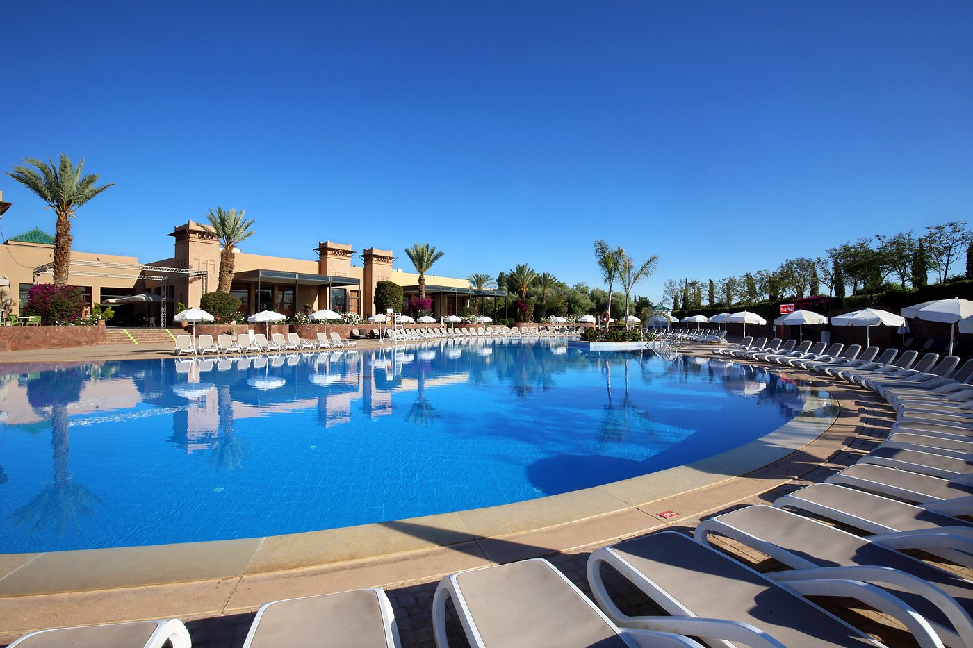 A large outdoor pool with surrounding lounge chairs and umbrellas at a luxury resort.